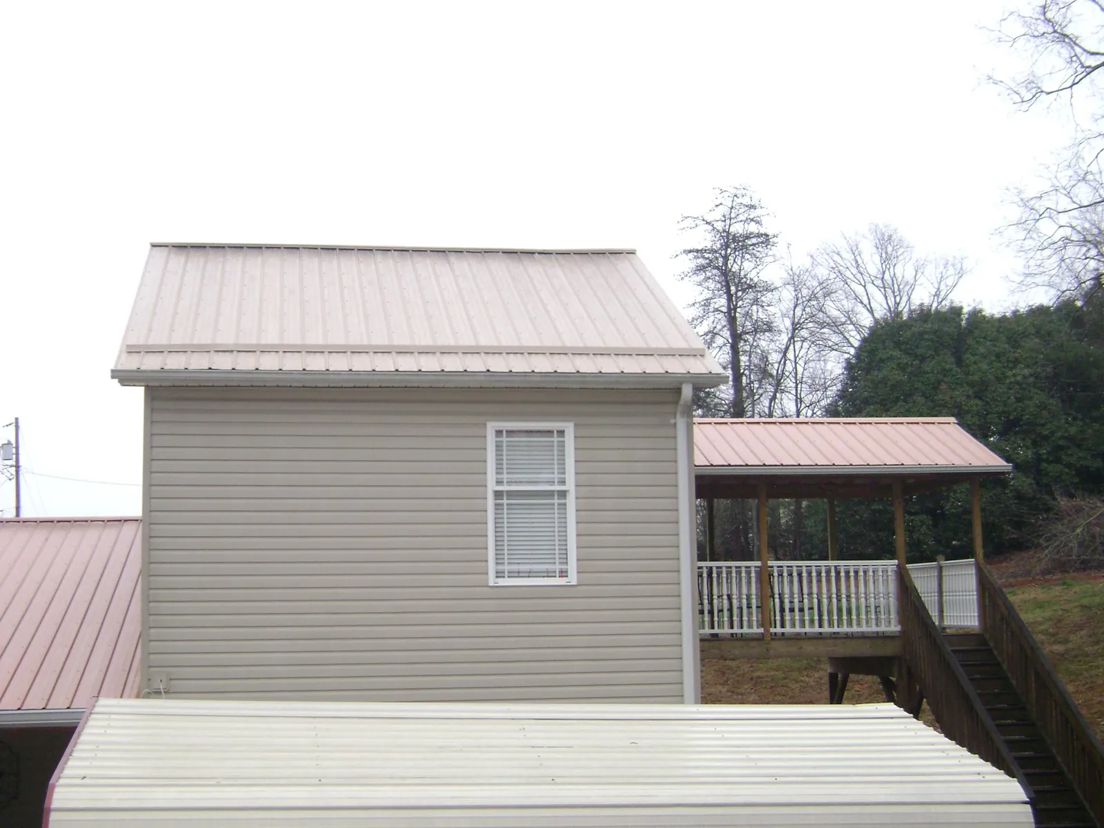 Tan metal roofs on a two story addition and attached porch, from a Roof Replacement job in Frederick